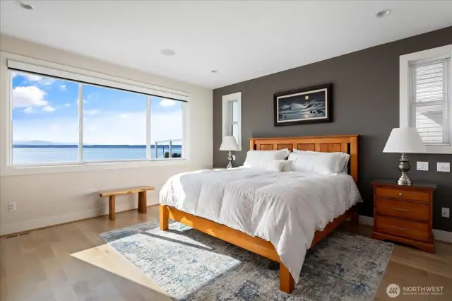 This luxurious main-floor primary suite is a private waterside retreat. A warm fireplace sets the tone for relaxation, while French doors lead directly to the waterside hot tub, allowing you to enjoy the sparkling Puget Sound views in ultimate comfort and style.