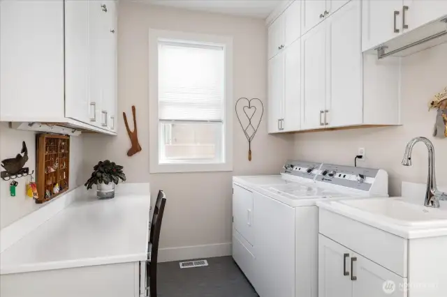 his well-appointed mudroom and laundry space combines practicality and style. Floor-to-ceiling built-in storage keeps everything organized, while a generous laundry sink handles tasks with ease. A built-in desk adds a convenient workspace, making this area both highly functional and beautifully designed for everyday living