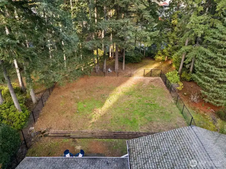 Fully fenced backyard with wooded greenspace beyond.
