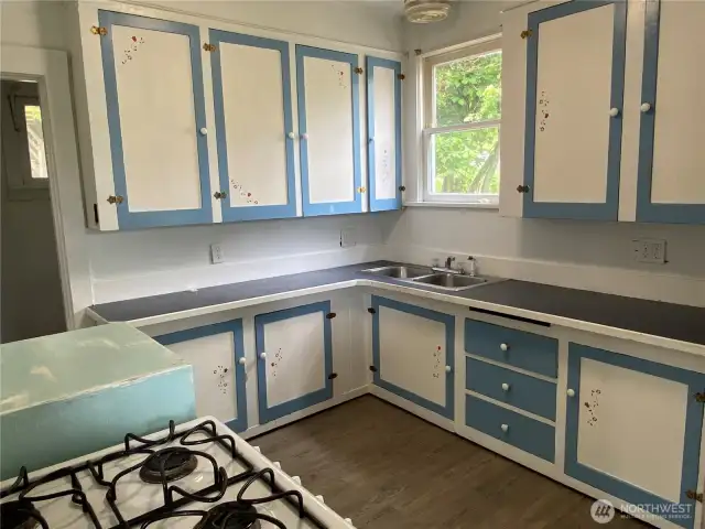 Kitchen is cute and spacious with a vintage feel.