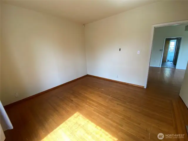 View of bedroom looking into living room. Notice the original wood flooring, still in really good shape.