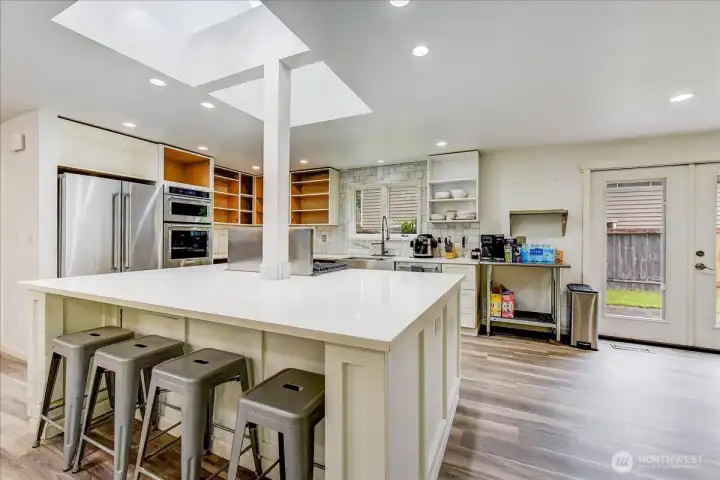 Large, sun-drenched kitchen featuring an expansive center island with a spacious breakfast bar.