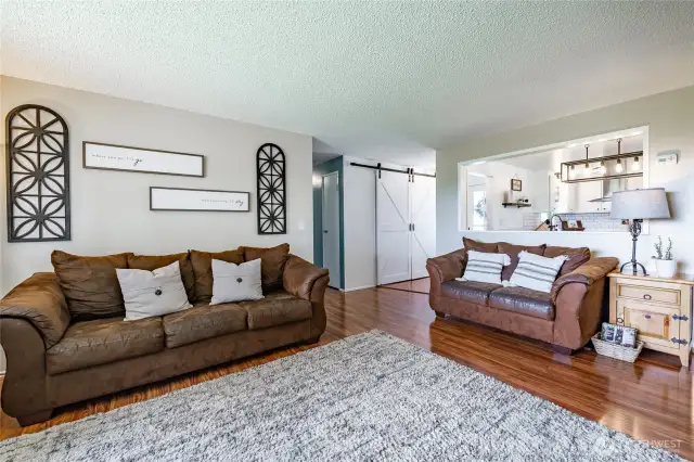 Living Room with glimpse of hall to entry with barn door pantry and hall leading to 3 bedrooms and full bath