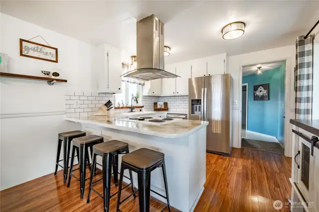 Kitchen with breakfast bar looking to hall that leads to laundry, back bath and family room