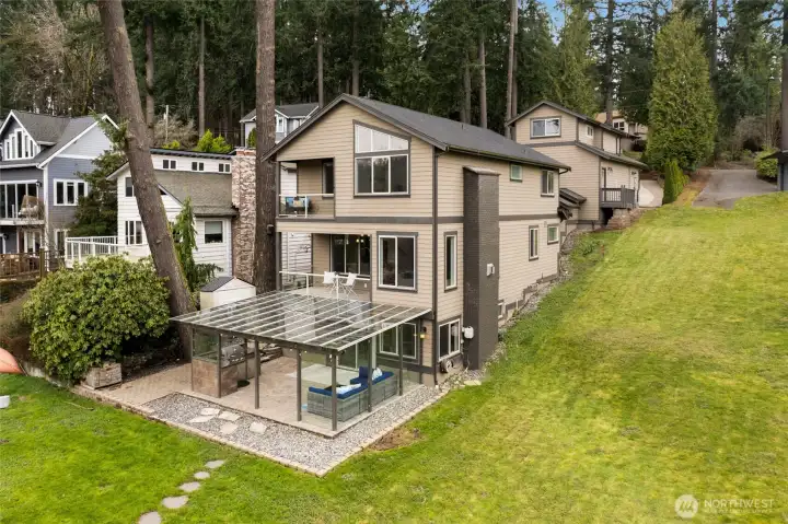 Backside of the home features covered patio, steps to the lake and ADU on top of garage with private entrance.