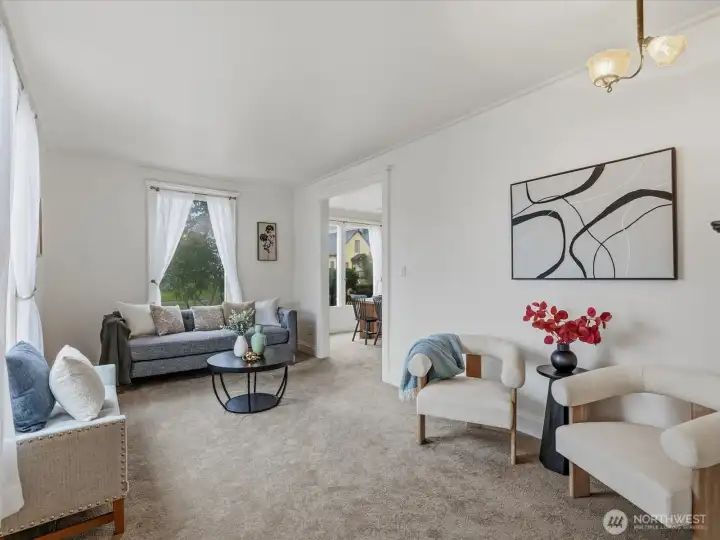 The living room is bright and welcoming. High ceilings add to the spacious feel.