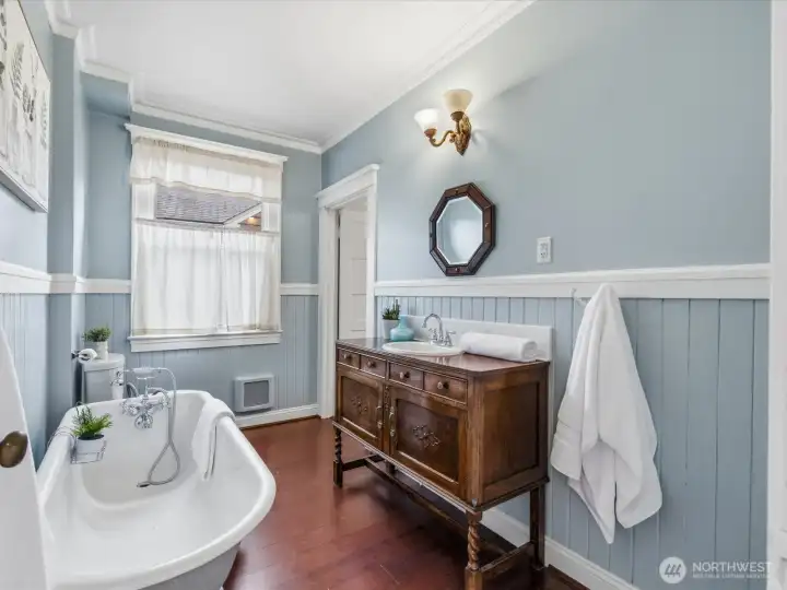 The main level full bath. Beautifully finished with an antique dresser as the vanity, the clawfoot 6' soaking tub, and wainscoting.