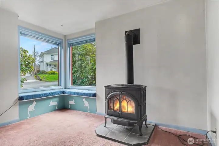 Charming bay-window nook with built-in seating and a gas stove, showcasing classic features and providing a warm, character-filled corner with room for future improvements.