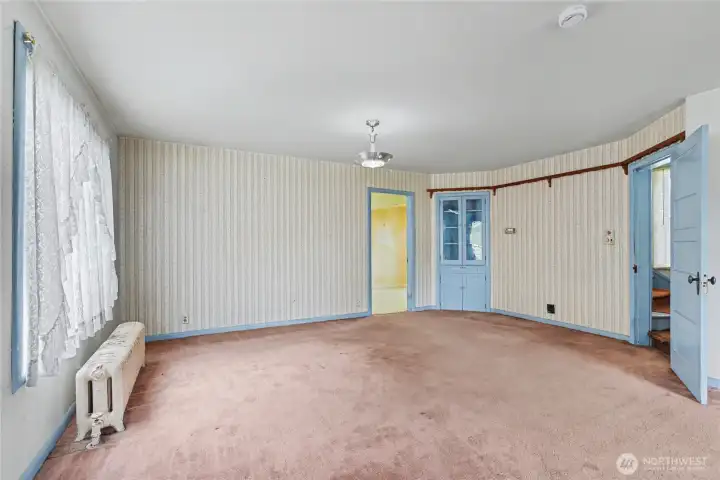 Light-filled dining or flex room with vintage wallpaper, built-in storage, and original architectural details—ideal for buyers seeking a project with strong bones and period charm.