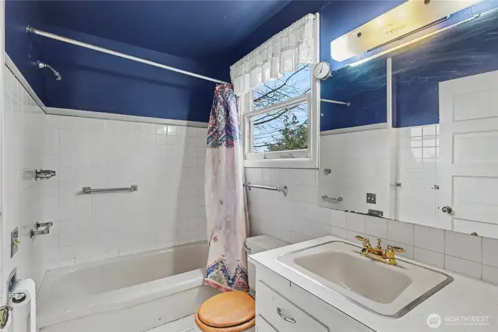 Full bathroom with vintage fixtures, classic tilework, and natural light, presenting a clean, functional space with opportunity for cosmetic updates.