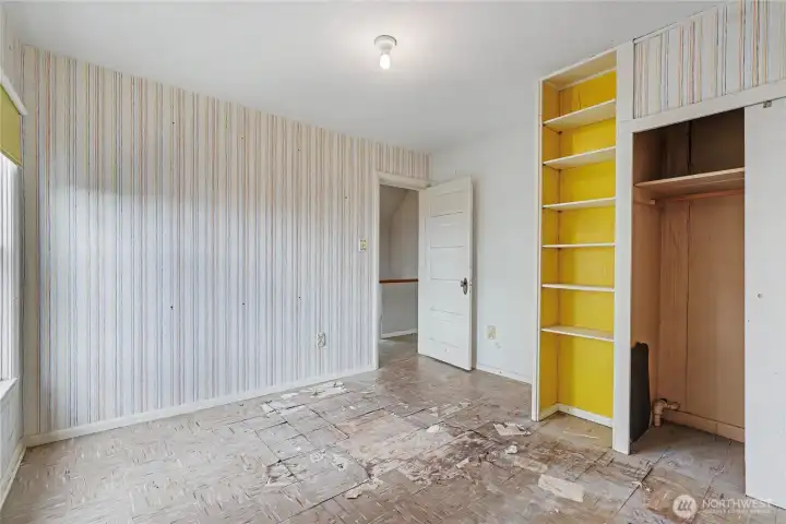 Third bedroom with built-in shelving, and exposed closet area, providing a clear opportunity for restoration or reconfiguration to suit modern needs.