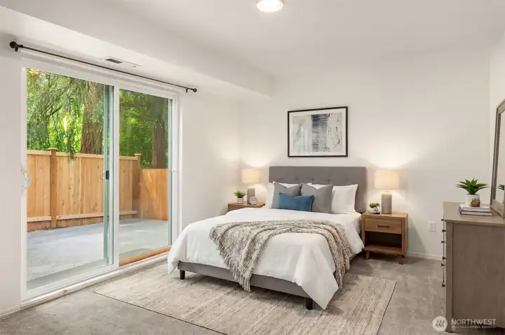 Virtually staged lower bedroom with sliding door to the backyard.