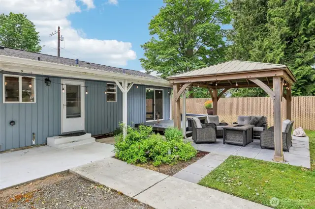 There is a welcoming back yard with a raised flower bed (to the right of photo) . See the beautiful Gazebo? The concrete detached blocks will stay if requested (under gazebo)....the large rose quartz rock is personal and will not stay, is property as well as the patio furniture. but you can see how wonderful you can make this your own...