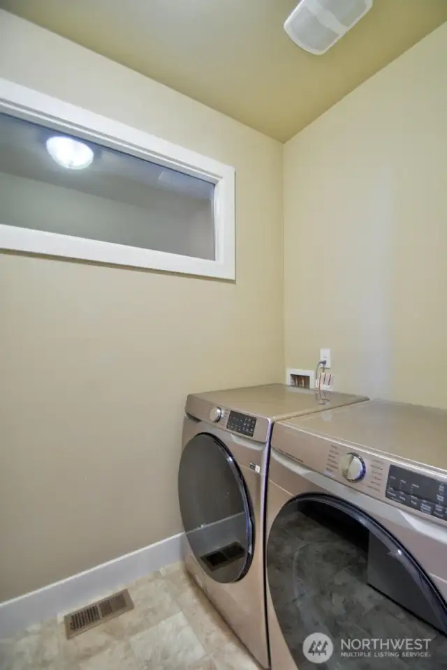 Upstairs utility room has front load washer/dryers and deep utility sink, cabinets, counter and clothes bar.