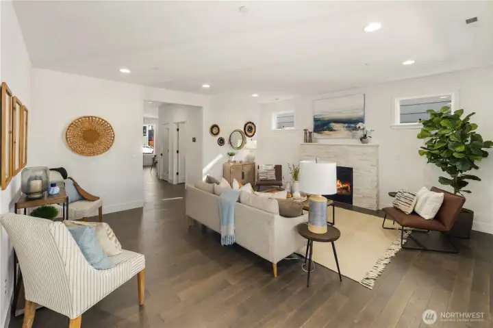 Great Room  This main living area offers a seamless layout designed for connection and comfort. Wide plank flooring runs throughout, while recessed lighting and expansive sightlines create an open, cohesive feel. A modern fireplace with textured surround anchors the room, adding warmth and architectural interest against clean, contemporary lines.    Situated in Bothell near Canyon Park amenities, this integrated living space reflects the elevated design standards associated with high-end contemporary homes. The connected flow supports both everyday living and effortless entertaining within a thoughtfully built residence served by the Northshore School District.    These photos are from a past Robinson Plan at a different community, so overall plan, colors, building orientation, finishes, home outlook, and other details can and WILL vary. All photos, renderings, site maps, and floorplans are for visualization purposes only.