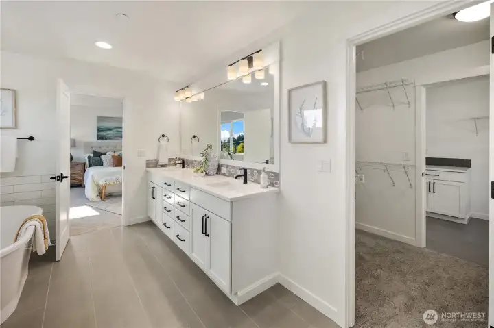 Primary Bath with Direct Laundry Access  This primary bathroom showcases a dual-sink vanity with quartz countertops, matte black fixtures, and a full-width mirror that enhances light and scale. Clean tile lines and durable flooring reinforce the spa-inspired design while maintaining everyday functionality.    A unique pass-through layout connects the en suite to the walk-in closet and onward to the laundry room, offering direct laundry access for added convenience. Located in Bothell near Canyon Park amenities, this thoughtful configuration reflects the innovation and quality associated with modern luxury new construction within the Northshore School District.    These photos are from a past Robinson Plan at a different community, so overall plan, colors, building orientation, finishes, home outlook, and other details can and WILL vary. All photos, renderings, site maps, and floorplans are for visualization purposes only.