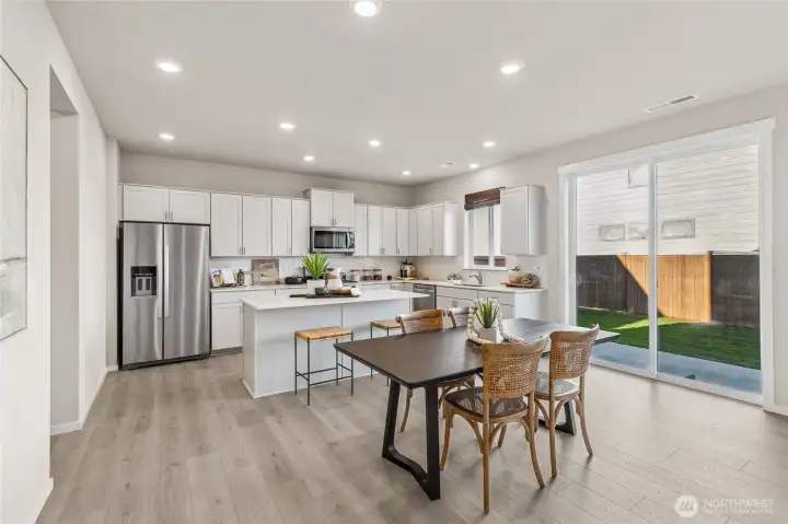 Bright kitchen with light cabinetry, stainless steel appliances, center island with bar seating and sliding glass door to the backyard. Photos are representative only and may display different color package and/or upgrades.