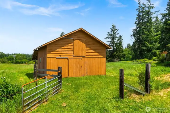 Well built barn with 2 stalls, a slab floor outside of the stalls and a large hay loft above.