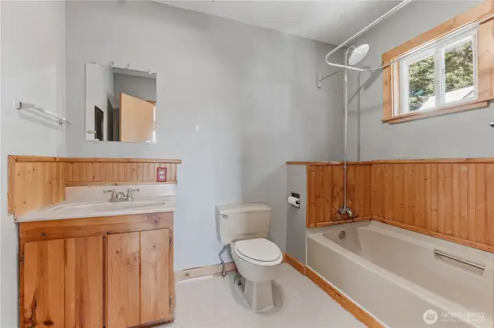 Full primary bath ensuite has wood cabinets & wainscoting.