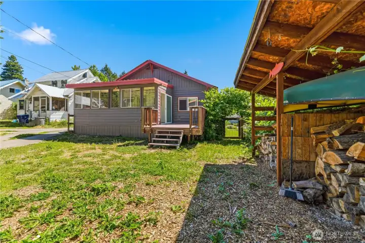 Back of home. Sun room & deck in back yard. Gate to the L. encloses the back yard & firewood storage shed.