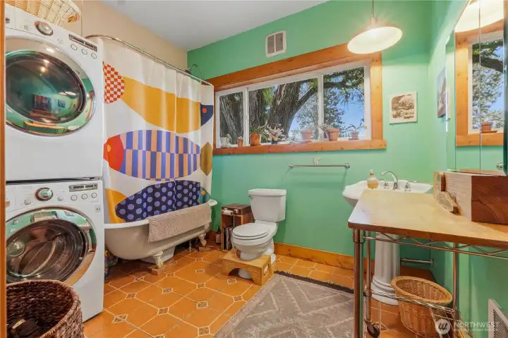 Full bathroom in rear flex space features a claw foot tub & stack washer/dryer.