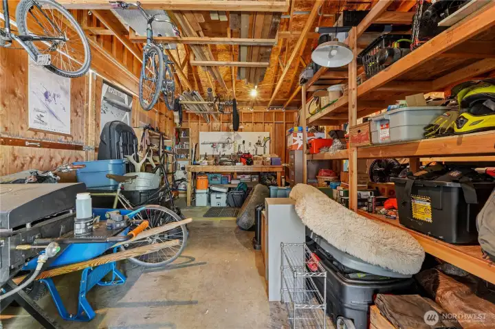 Garage space has lots of storage with shelves & workshop area.