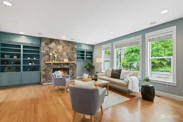 Family room boasts a gas fireplace surrounded by beautiful stone and built-in cabinets with a wall of windows providing a light-filled main level!