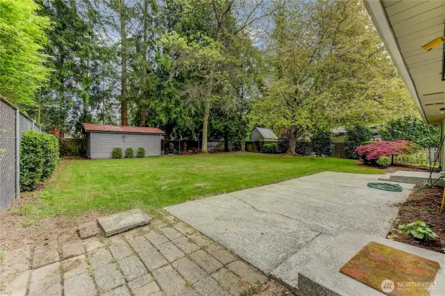 Large back yard with mature landscaping and storage shed.