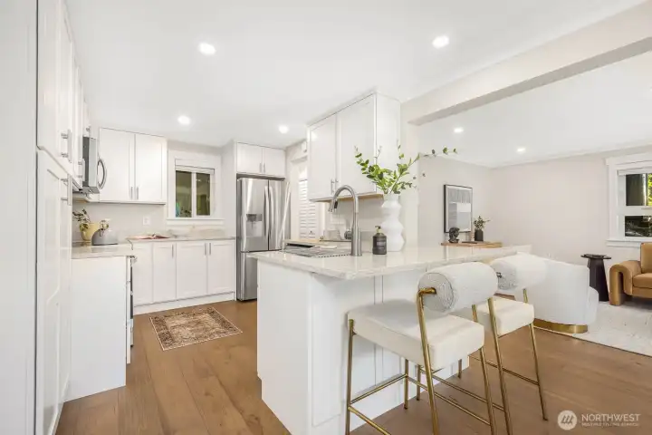 Freshly updated kitchen featuring crisp white cabinetry, quartz counters, and stainless steel appliances, including a brand-new range.