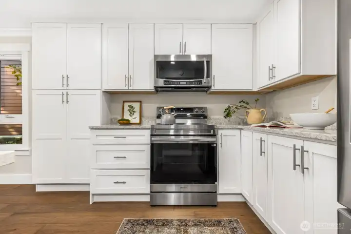 Freshly updated kitchen featuring crisp white cabinetry, quartz counters, and stainless steel appliances, including a brand-new range.
