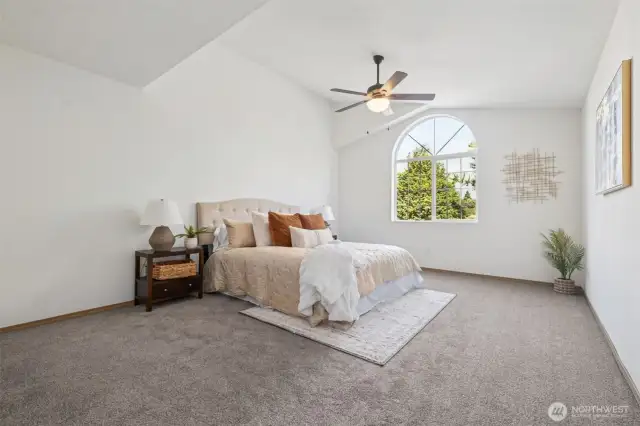 There is ample room in this well appointed primary bedroom with vaulted ceilings.