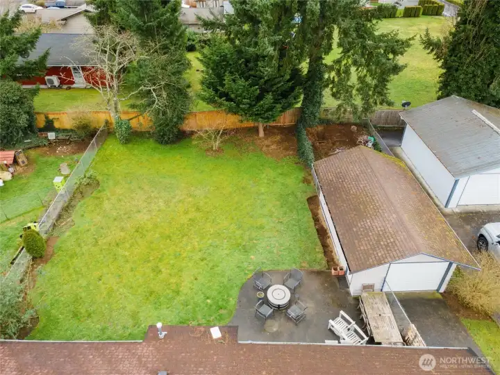 Aerial backyard view captures the large level lawn, patio space, detached garage, and outdoor flexibility.