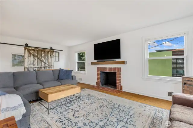 Another view of the living room with wood burning fireplace and sliding barn door that allows for access to the rest of the main floor.
