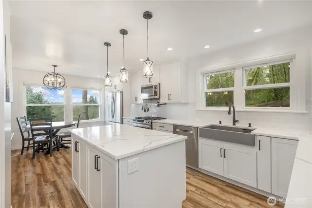 Fully renovated and modern kitchen with in-kitchen eating area, stainless appliances, farm style sink, quartz slab counters and center island.