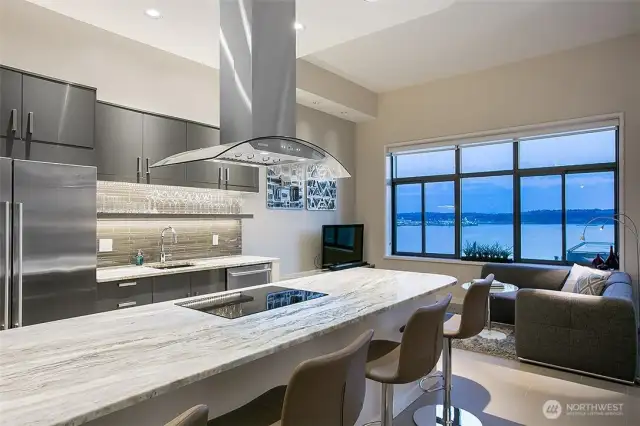 A show-stopping kitchen features a massive slab granite island with stainless vent hood.