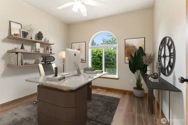Virtually staged bedroom (staged here as an office) with hardwood flooring and a half-moon, formerly called a lunette, window. Closet with built-in custom shelving and storage is to the left of the photo and ceiling fan.