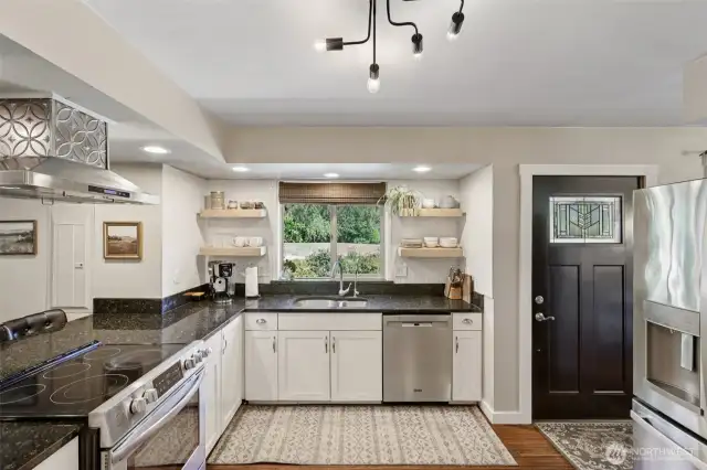 Recessed and decorative lighting paired with sleek stone countertops add a modern, welcoming feel to the eat-in kitchen.