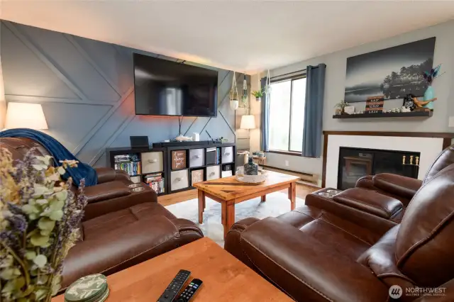 Enjoy a bright and open living space featuring a cozy wood-burning fireplace, ideal for relaxing on chilly evenings. TV Mount can stay for the new owner and as a convenience to seller.