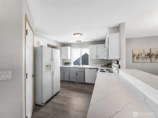 Kitchen view from the other side showing the gorgeous quartz countertops and the breakfast bar! So much counterspace for meal prep, making cookies, and don't forget homework time on the breakfast bar.