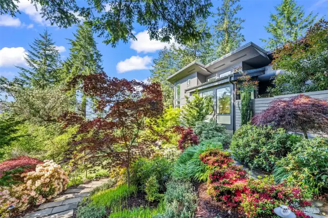 Manicured trails and artfully assembled plantings frame the home with seasonal color, creating a seamless connection between refined design and the organic beauty of Fox Island.