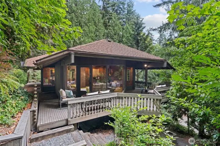 The expansive deck offers multiple seating areas and a graceful stairway leading to the lower level and garden, serving as a stunning centerpiece for both entertaining and relaxation.