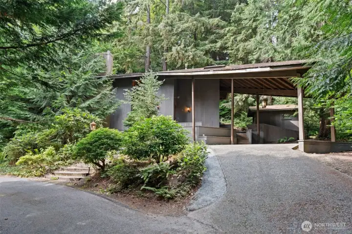 Arrive in style—this private drive leads to a striking covered carport, framed by lush evergreens for the perfect Pacific Northwest welcome.