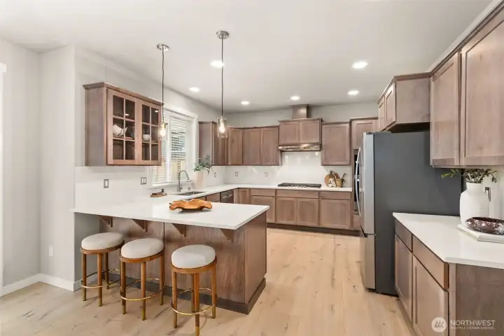 Sleek and modern kitchen with Quartz counters and full tile backsplash. Pendant lights hang above eating bar are perfect for casual meals or entertaining. Sleek and modern kitchen with Quartz counters and full tile backsplash. Pendant lights hang above eating bar are perfect for casual meals or entertaining.