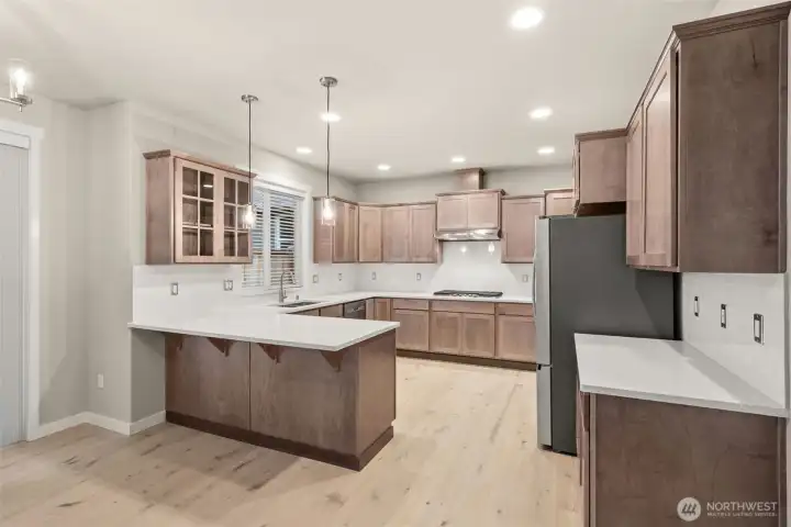 Sleek and modern kitchen with Quartz counters and full tile backsplash. Pendant lights hang above eating bar are perfect for casual meals or entertaining.