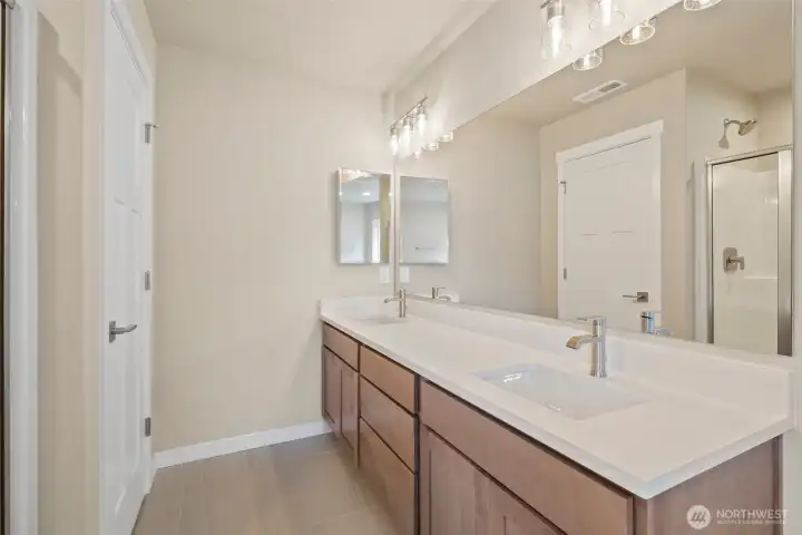 Primary bathroom with tile flooring and quartz countertops.