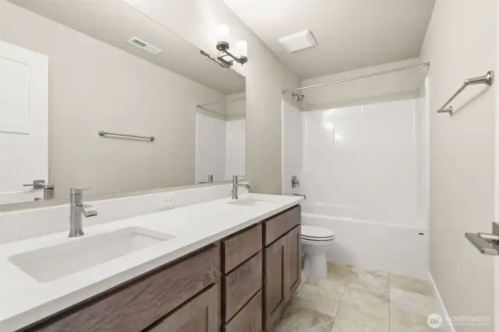 Main bathroom with dual sink vanity and quartz countertops.