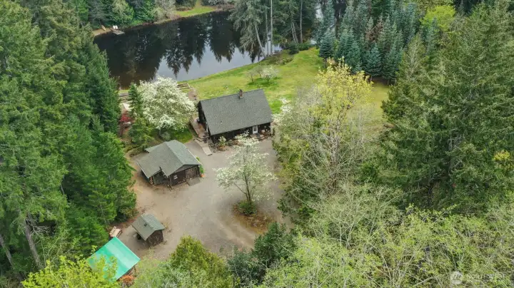 Bird’s-eye view showcasing the property’s privacy, prime lake frontage, and versatile outbuildings.