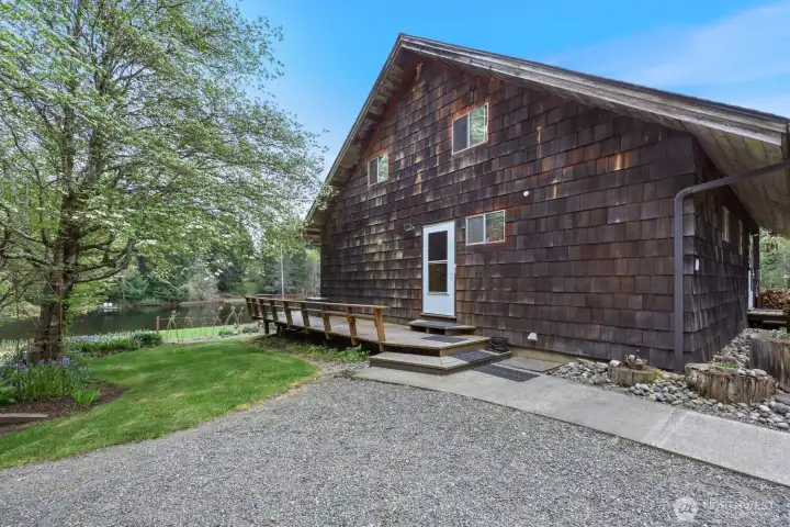 Convenient side entrance next to the shop leads to the start of the wraparound deck, with the garden and greenhouse just beyond the lawn.