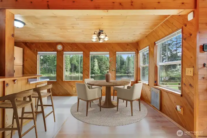 Alternate view of the dining space, where a wall of windows brings the outdoors in. Virtually staged to showcase possibilities.