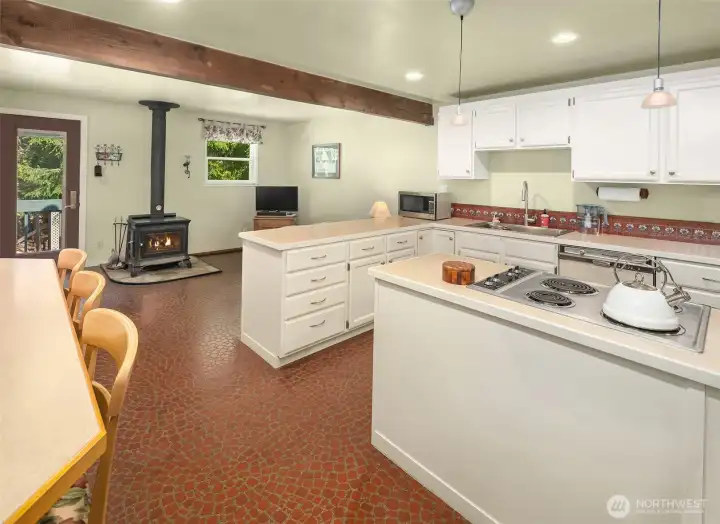 Kitchen has very generous countertops and storage, eating bar and space for a desk. Adjacent sitting area has soapstone wood stove and direct access to north side of home. Everything is so well-cared-for and clean; there is real pride of ownership here!
